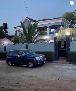 a blue car parked in front of a house at The Retreat Apartments in Brusubi