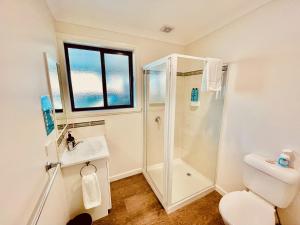 a bathroom with a shower and a toilet and a sink at Bays Rest in St Helens