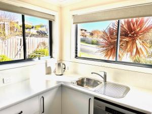 een keuken met twee ramen en een wastafel bij Bays Rest in St Helens