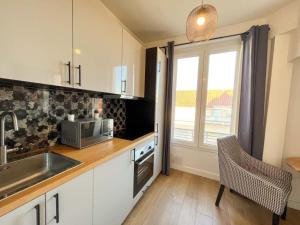 a kitchen with white cabinets and a sink and a window at Suite Nairobi in Villeurbanne