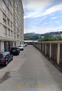 a parking lot with cars parked next to a building at Appartement T4 des jardins in Chambéry