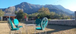 three chairs sitting in the grass with mountains in the background at Cabaña Mis Montañas in La Rioja