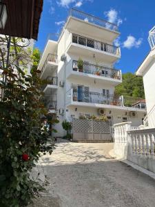 a white apartment building with balconies and a fence at Fortunella Apartments in Herceg-Novi