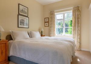 a bedroom with a white bed and a window at Old Rectory Cottage in Orford