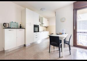 a kitchen with white cabinets and a table and chairs at House of Lake Garda in Castelnuovo del Garda