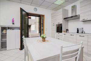 a white kitchen with a white table and chairs at Saint Simplicio House in Olbia