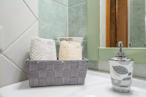 a basket of towels and a bottle on a bathroom sink at Saint Simplicio House in Olbia +15 photos