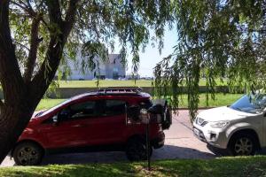 a red car is parked next to a tree at MdP, 2 dorm, 4 pers, 2 cuadras de la playa in Mar del Plata