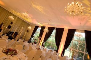 uma sala de jantar com mesas e cadeiras brancas e um lustre em Nells Park Hotel em Trier