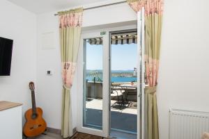 Zimmer mit einer Tür und einem Balkon mit einer Gitarre in der Unterkunft Apartments Galic in Šibenik
