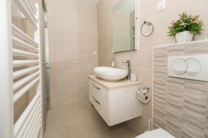 ein weißes Badezimmer mit Waschbecken und Spiegel in der Unterkunft Apartments Galic in Šibenik + 37 Fotos