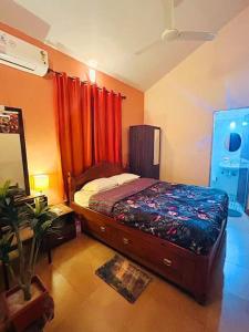 a bedroom with a bed with red curtains at Reev's Homestay: Luxury 2 Bedroom apartment in Arossim-Cansaulim