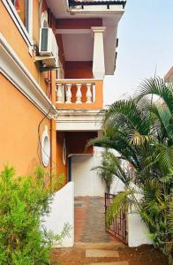 a building with a balcony and a palm tree at Reev's Homestay: Luxury 2 Bedroom apartment in Arossim-Cansaulim