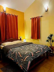 1 dormitorio con 1 cama y cortinas rojas en Reev's Homestay: Luxury 2 Bedroom apartment en Arossim-Cansaulim
