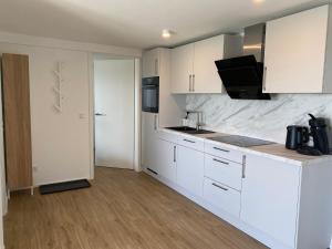 een keuken met witte kasten en een aanrecht bij Apartment Kaapi in Friedrichshafen
