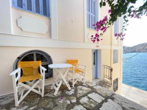 a table and chairs on a balcony with a view of the water at Anamar Symi Residences in Symi