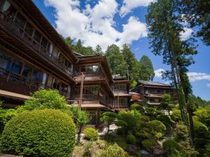 einen Blick nach außen auf ein Gebäude mit Bäumen und Sträuchern in der Unterkunft Yunoshimakan in Gero