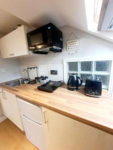 a kitchen counter with a sink and a microwave at Alross studio flat / private bathroom in London
