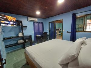 1 dormitorio con 1 cama blanca y paredes azules en Pura Vida Aparment - Downtown La Fortuna, en Fortuna
