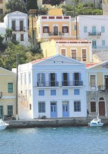 a white building on the water next to buildings at Anamar Symi Residences in Symi