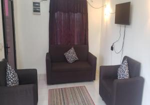 Mohans Apartments في Nausori: غرفة معيشة مع كرسيين وأريكة