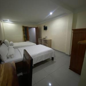 una camera d'albergo con due letti e una televisione di Pesona Room and restaurant a Labuan Bajo