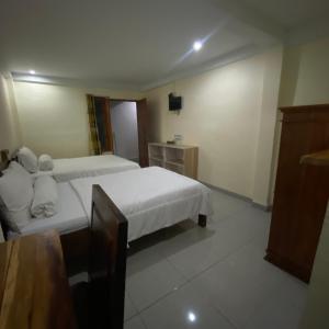um quarto de hotel com duas camas e uma televisão em Pesona Room and restaurant em Labuan Bajo