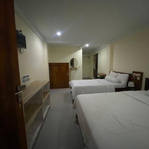 una camera d'albergo con tre letti e una televisione di Pesona Room and restaurant a Labuan Bajo