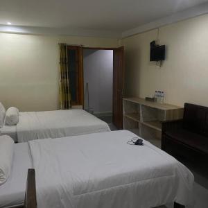 a hotel room with two beds and a television at Pesona Room and restaurant in Labuan Bajo