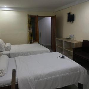 Habitación de hotel con 2 camas y TV en Pesona Room and restaurant, en Labuan Bajo
