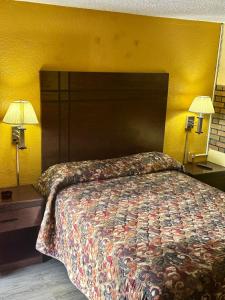 a bedroom with a bed and two lamps and a yellow wall at Motel 301 in Tampa