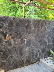 a stone wall with a shower in a yard at Gili Matiki in Gili Air