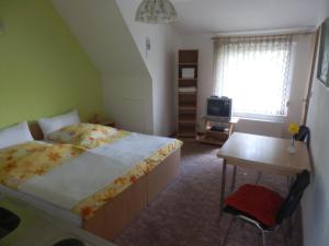 a bedroom with a bed and a desk and a television at Bramkamp Pension in Dallgow