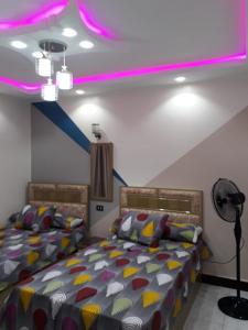 - une chambre avec 2 lits et un éclairage violet dans l'établissement Khaled new home, au Caire
