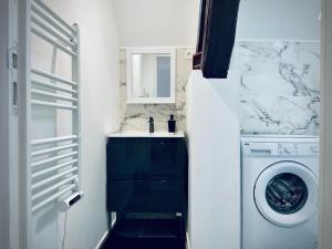 uma casa de banho com uma máquina de lavar roupa e um lavatório em La Perle em Montargis