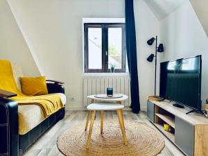 uma sala de estar com uma cama, uma mesa e uma televisão em La Perle em Montargis
