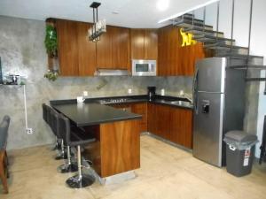 a kitchen with wooden cabinets and a stainless steel refrigerator at Hermosa Casa en Orilla del lago -Zona de villedos- in San Cristóbal Zapotitlán