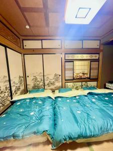 a bedroom with a bed with blue sheets at T&T Fujiyama Guest House in Fujiyoshida