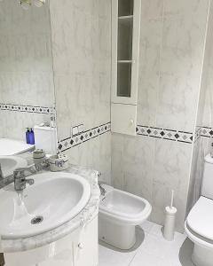 a white bathroom with a sink and a toilet at Apartamento San Roque in Betanzos