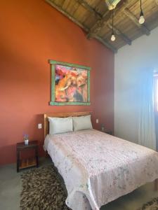 a bedroom with a bed and a painting on the wall at Pousada Recanto Mandalah in Cunha