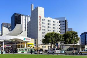 a large white building with cars parked in front of it at Kumamoto Tokyu REI Hotel in Kumamoto