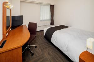 ein Hotelzimmer mit einem Bett und einem Schreibtisch in der Unterkunft Kumamoto Tokyu REI Hotel in Kumamoto