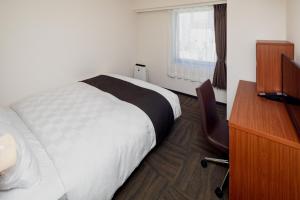 a bedroom with a bed and a desk and a window at Kumamoto Tokyu REI Hotel in Kumamoto