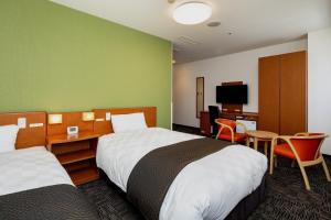 ein Hotelzimmer mit 2 Betten und einem TV in der Unterkunft Kumamoto Tokyu REI Hotel in Kumamoto