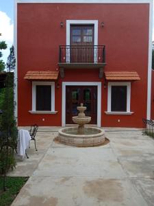 a red house with a fountain in front of it at Hacienda San Jose Poniente in Hoctún