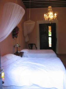 a bedroom with two white beds and a chandelier at Hacienda San Jose Poniente in Hoctún
