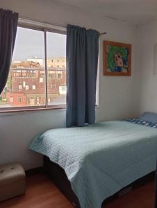 um quarto com uma cama em frente a uma janela em La Casa de la Pulperia en Cerro Alegre em Valparaíso
