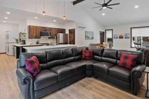 a living room with a black leather couch and a kitchen at Luxe Mt. Rainier Lodge w/ Hot Tub-AC-Game Room in Ashford