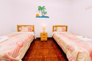 a bedroom with two beds and a wooden floor at Hospedaje Mary in Paracas