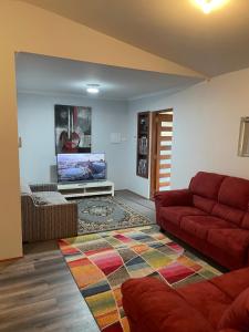 a living room with a red couch and a flat screen tv at Quaint Flat, Outside Dog Friendly, near hospital in Geraldton